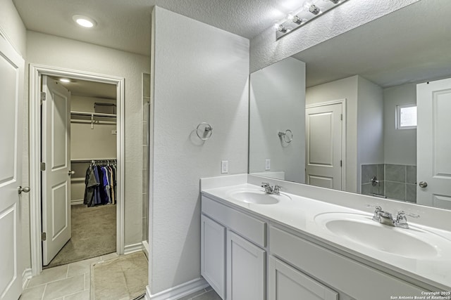 bathroom featuring double vanity, tile patterned floors, a spacious closet, and a sink