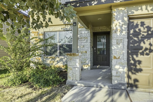 view of exterior entry featuring a garage and stone siding