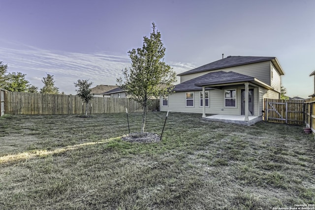 back of property with a fenced backyard, a gate, a patio, and a lawn
