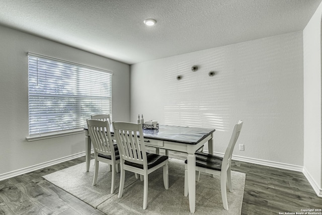 dining area featuring baseboards, a textured ceiling, and wood finished floors