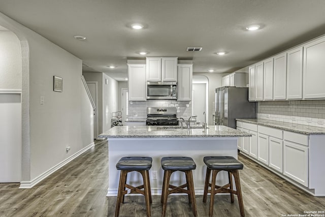 kitchen with backsplash, visible vents, arched walkways, stainless steel appliances, and dark wood-type flooring