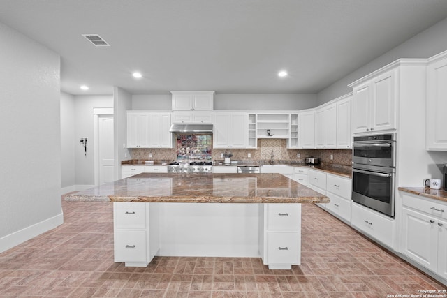 kitchen with visible vents, open shelves, baseboards, a center island, and under cabinet range hood