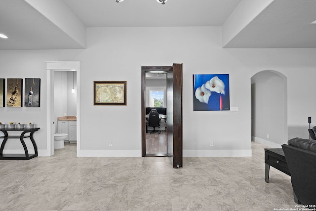 living area featuring arched walkways and baseboards