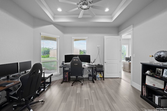 office space featuring crown molding, a ceiling fan, a tray ceiling, and wood finished floors