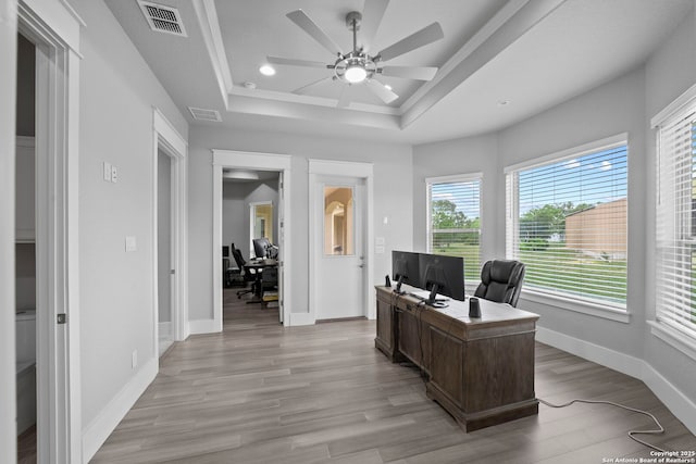 office area featuring a wealth of natural light, a ceiling fan, a tray ceiling, and visible vents