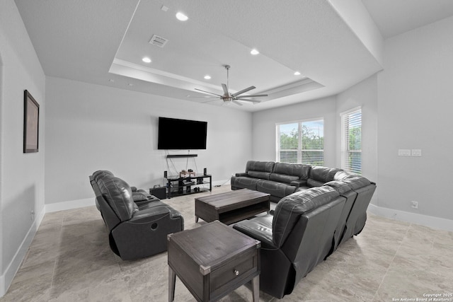 living room featuring ceiling fan, visible vents, baseboards, a tray ceiling, and recessed lighting