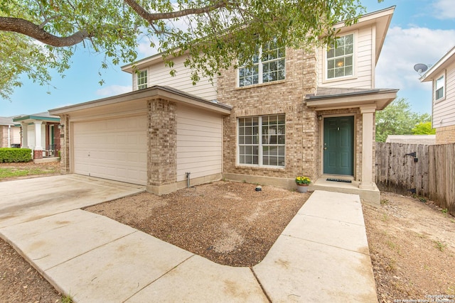 traditional home featuring fence, an attached garage, concrete driveway, and brick siding