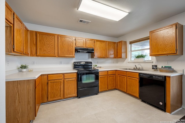 kitchen featuring visible vents, brown cabinets, a sink, black appliances, and under cabinet range hood