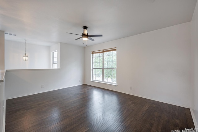 unfurnished room featuring visible vents, a ceiling fan, baseboards, and dark wood-style floors