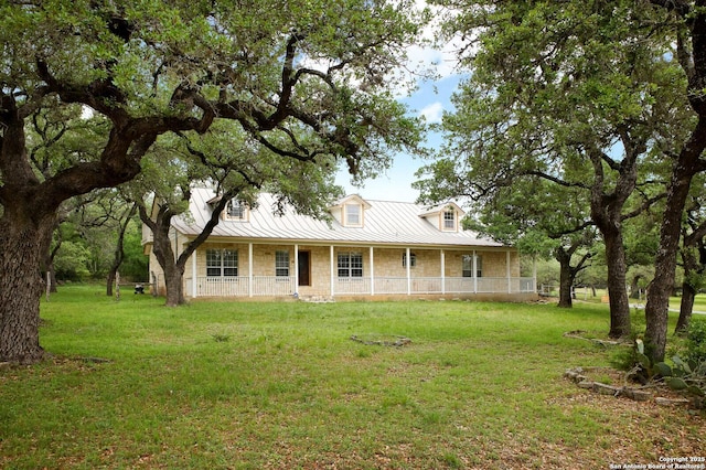 farmhouse inspired home with a standing seam roof, covered porch, metal roof, and a front lawn