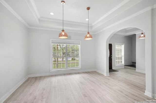 interior space featuring crown molding, arched walkways, a raised ceiling, baseboards, and light wood-style floors