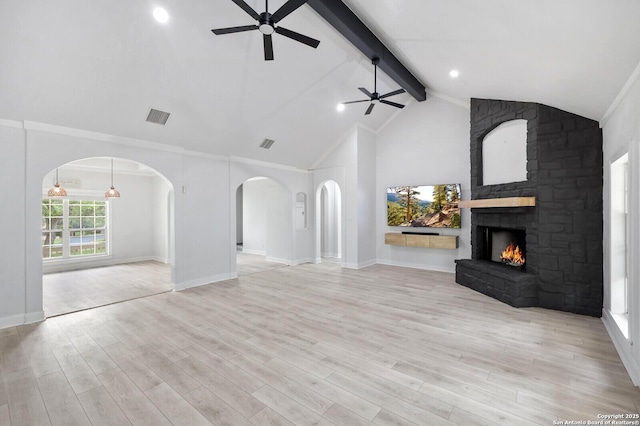unfurnished living room with ceiling fan, beam ceiling, arched walkways, light wood-type flooring, and visible vents