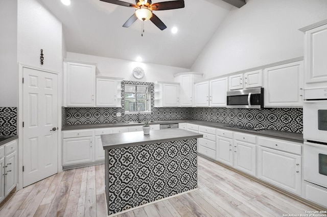kitchen featuring dark countertops, a sink, white double oven, a ceiling fan, and stainless steel microwave