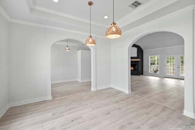 unfurnished dining area with visible vents, arched walkways, wood finished floors, and a tray ceiling