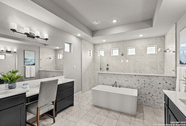 full bathroom with vanity, marble finish floor, a walk in shower, and a freestanding bath