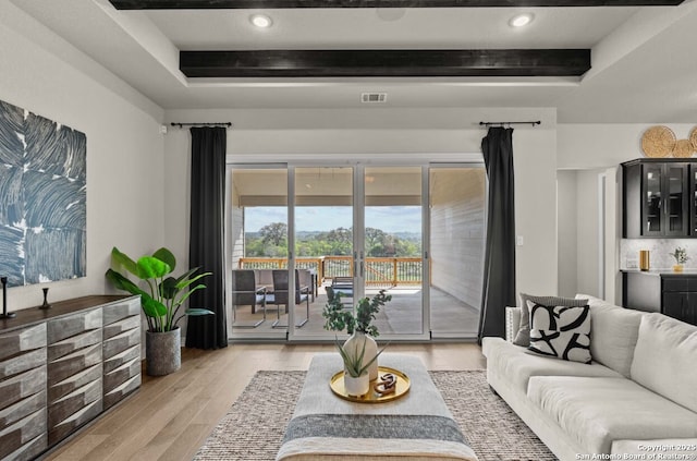 living room featuring recessed lighting, a raised ceiling, light wood finished floors, and visible vents