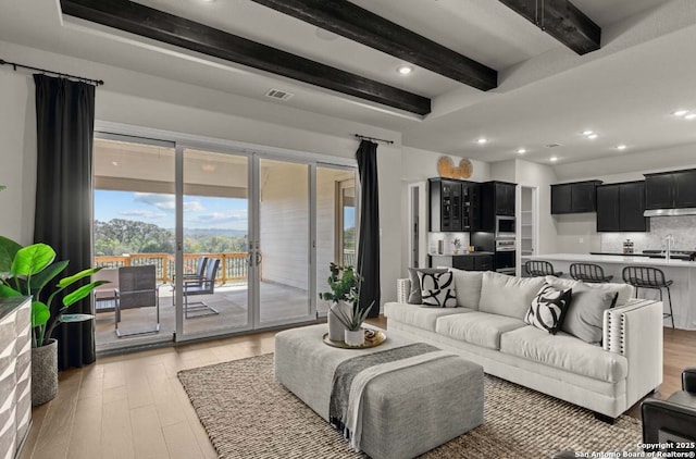 living room featuring recessed lighting, visible vents, beam ceiling, and light wood-style flooring