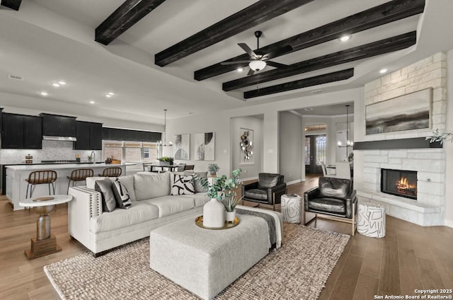 living area with ceiling fan, a fireplace, recessed lighting, wood finished floors, and beamed ceiling