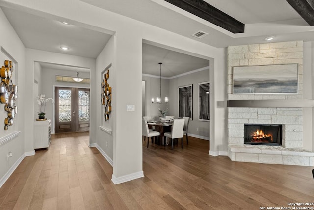 foyer with a chandelier, baseboards, visible vents, and wood finished floors