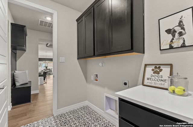 clothes washing area featuring washer hookup, electric dryer hookup, visible vents, cabinet space, and baseboards