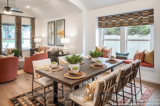 dining space featuring a ceiling fan, arched walkways, vaulted ceiling, light wood-style floors, and recessed lighting