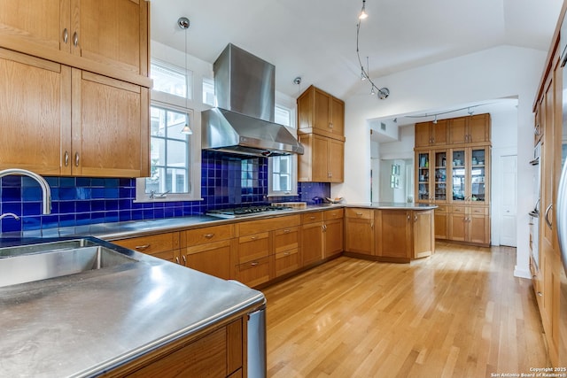 kitchen featuring a sink, light wood finished floors, stainless steel countertops, stainless steel gas cooktop, and island exhaust hood