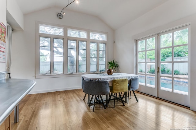 dining space with baseboards, lofted ceiling, and light wood-type flooring