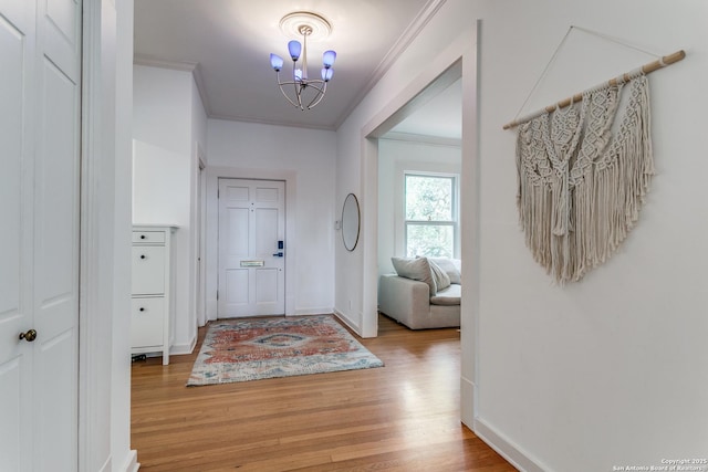entrance foyer with crown molding, baseboards, light wood-style floors, and a chandelier
