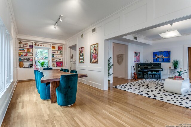 dining area featuring crown molding, rail lighting, and light wood-type flooring