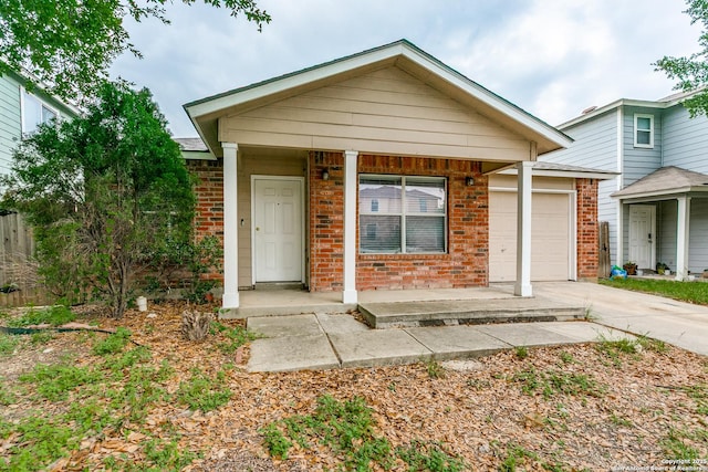 single story home with a porch, brick siding, an attached garage, and concrete driveway