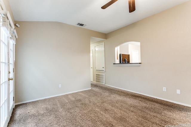 carpeted empty room with baseboards, a ceiling fan, lofted ceiling, and visible vents