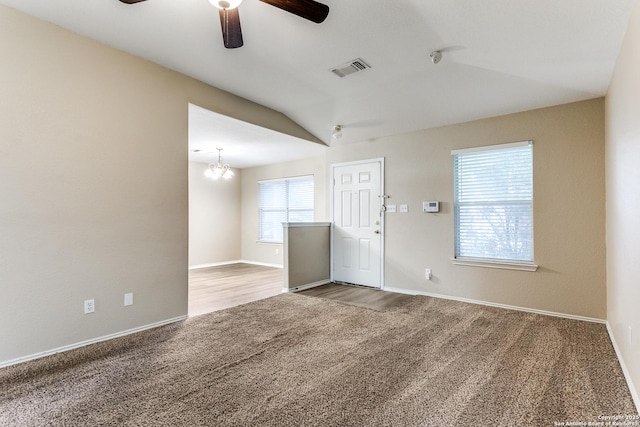 unfurnished room with visible vents, vaulted ceiling, carpet floors, baseboards, and ceiling fan with notable chandelier