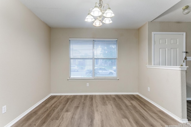 unfurnished dining area featuring baseboards, wood finished floors, and a chandelier