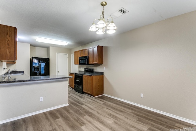 kitchen featuring baseboards, black appliances, wood finished floors, and visible vents