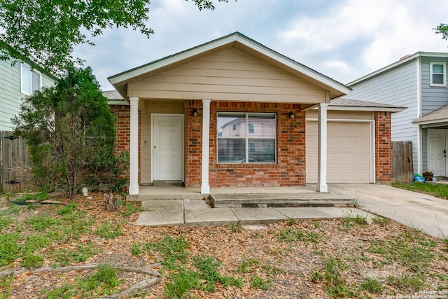 ranch-style home with a porch, driveway, brick siding, fence, and an attached garage