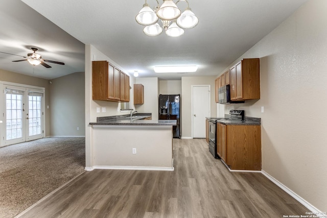 kitchen featuring brown cabinets, dark countertops, black appliances, and light wood-type flooring