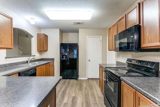 kitchen with visible vents, light wood-type flooring, a textured ceiling, a sink, and black appliances