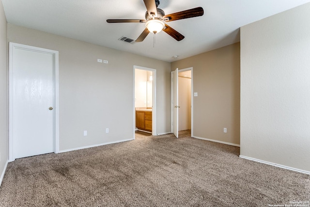 unfurnished bedroom featuring visible vents, baseboards, light colored carpet, a ceiling fan, and ensuite bath