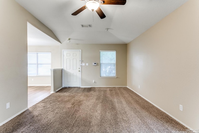 unfurnished room featuring visible vents, carpet floors, lofted ceiling, baseboards, and a ceiling fan