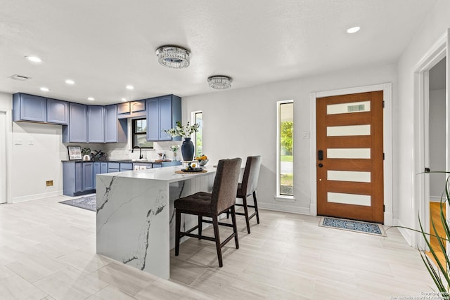 kitchen featuring baseboards, blue cabinetry, a sink, and a kitchen bar
