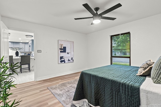 bedroom with baseboards, a ceiling fan, and light wood-style flooring