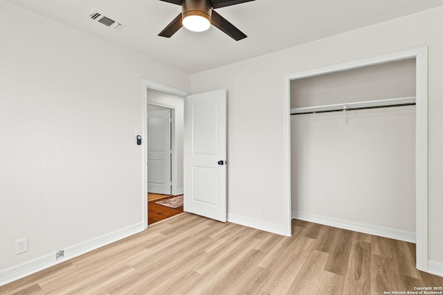 unfurnished bedroom featuring visible vents, a closet, wood finished floors, baseboards, and a ceiling fan