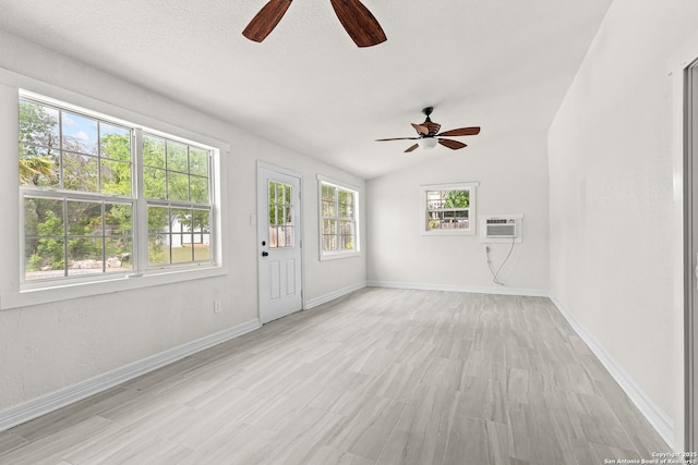 interior space with light wood-style floors, baseboards, ceiling fan, and a wall mounted AC