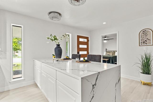 kitchen with light stone counters, baseboards, a peninsula, and white cabinets