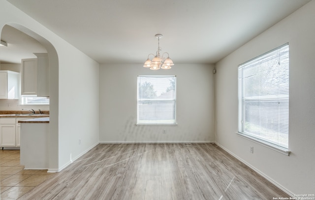 unfurnished dining area with a sink, plenty of natural light, and light wood-style flooring