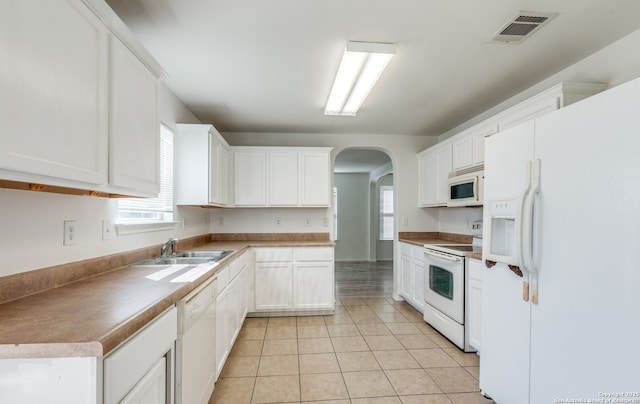 kitchen with visible vents, arched walkways, a sink, white appliances, and white cabinetry