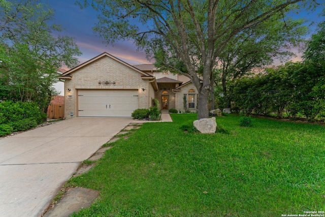 view of front facade with brick siding, an attached garage, a yard, and driveway