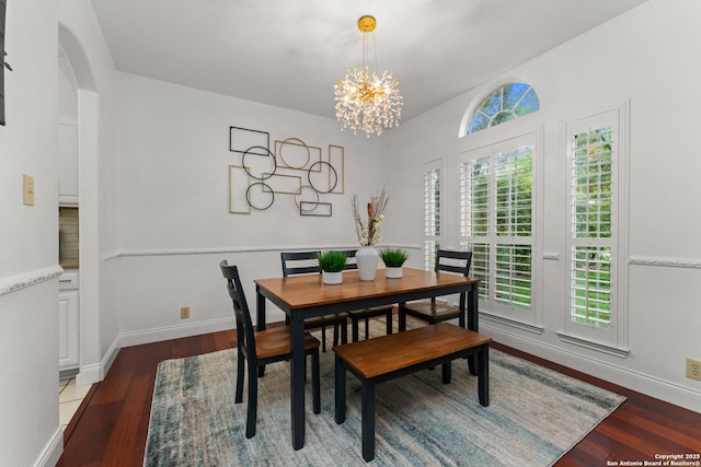 dining area featuring baseboards, lofted ceiling, wood finished floors, and a chandelier