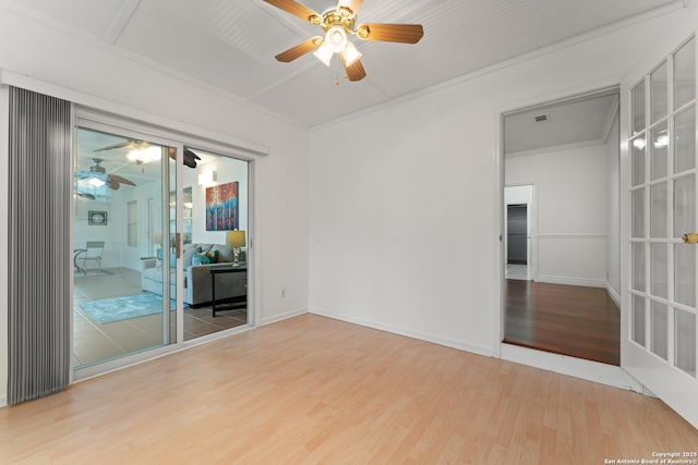 empty room with crown molding, ceiling fan, visible vents, and wood finished floors