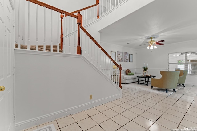 interior space featuring crown molding, a ceiling fan, baseboards, and tile patterned flooring